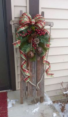 a wooden sled with christmas decorations on the front door and wreath hanging from it's side