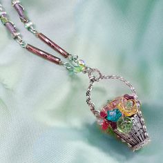 "This charming gift of flowers lasts forever. Entirely fabricated by hand, each of its elements is created from vintage tooling. Inside, a delicate arrangement of old European glass flowers and leaves features soft colors of spring -- pink, aqua, lilac, yellow and peridot. The basket pendant dangles from a chain of alternating twisted lilac glass and links with crystal accented winding leaves. Hand burnished silver finish. Made in our Los Angeles studio. Chain: 30\" Basket: 2\" x 1\"" Homemade Door Wreaths, May Flower, Basket Pendant, Aqua Earrings, Bangle Bracelet Set, Skulls And Roses, Sweet Romance, Bird Jewelry, Moon Jewelry