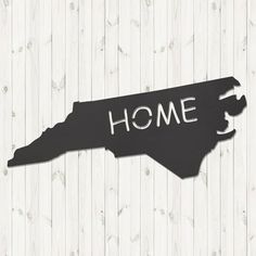 a wooden sign that says home with the shape of a state in white and black