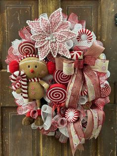 a christmas wreath with a teddy bear and candy canes on the front door,