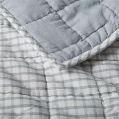 an unmade bed with a blue and white checkered comforter