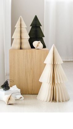 three folded paper trees sitting on top of a wooden block