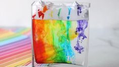 an art project made with colored paper and watercolors in a glass container on a table