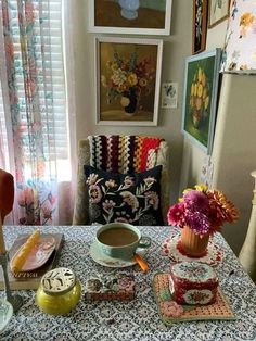 a table topped with plates and cups filled with food next to a window covered in curtains