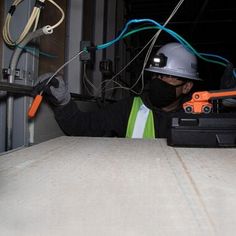 a man in a hard hat and safety gear working on wires