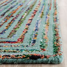 an area rug with multicolored stripes and fringes on the bottom, along with a wooden floor