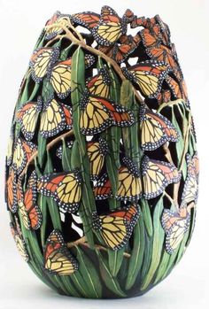 a vase with many butterflies on it and green stems in the center, against a white background