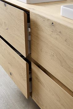 a bathroom sink sitting next to a wooden cabinet with drawers on it's sides