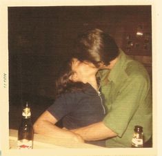 a man and woman sitting at a table with beer bottles