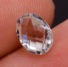 a close up of a person's hand holding an oval shaped diamond