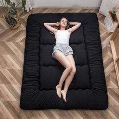 a woman laying on top of a black mattress