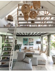 a living room filled with lots of furniture under a ceiling mounted light fixture and wicker baskets hanging from the rafters