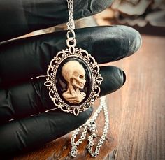 There is no better way to show your gothic style than with a unique Victorian inspired cameo necklace. The cameo is cast from an original sculpt by me, hand painted, and clear coated for durability. Pendant measures approx 27mm long and hangs from an 18" chain Ships USPS Ground Gothic Hand-cast Halloween Necklaces, Black Gothic Necklace With Soldered Details, Steampunk Skull Jewelry Gift, Handmade Gothic Skull Necklace, Gothic Cameo Necklaces For Gifts, Gothic Cameo Necklaces As Gift, Gothic Cameo Necklace As Gift, Gothic Cameo Necklace For Gift, Gothic Hand Cast Collectible Necklaces