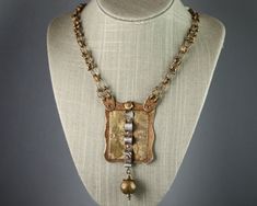 "Bronze chain necklace with large pendant composed of layered metals connected by rivets: Hammered Bronze, etched Brass, and hammered and formed Fine Silver.  A large Brass bead hangs from the bottom of the pendant. Chain is handmade with bronze wire. Dimensions of Pendant: Width at widest point 2\" (51 mm), length (including dangling bead) 4\" (102 mm). Total Necklace length:  21 3/4\" (552 mm)" Cheap Bronze Necklaces With Antique Finish, Hand Forged Gold Brutalist Jewelry, Brutalist Hand Forged Gold Jewelry, Gold Antique Finish Copper Necklaces, Gold Copper Necklace With Antique Finish, Bronze Hammered Bohemian Necklace, Brutalist Brass Jewelry In Bronze, Hammered Gold Copper Necklace, Gold Hammered Copper Necklace