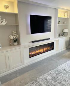 a living room with a large television mounted on the wall and a fire place in front of it