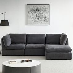 a living room with a gray couch and white coffee table in front of a painting on the wall