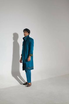 Featuring a teal overcoat with abstract hand paint detailing at the hem and collar. Paired with a tone on tone shirt kurta and tapered trousers. Blue Nehru Jacket For Festive Workwear, Festive Blue Nehru Jacket For Work, Festive Blue Nehru Jacket For Workwear, Elegant Blue Kurta For Winter, Blue Long Sleeve Kurta For Winter, Blue Long Sleeve Winter Kurta, Blue Formal Kurta For Winter, Blue Festive Winter Kurta, Blue Winter Festive Kurta