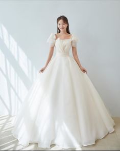 a woman in a white wedding dress posing for the camera with her hands on her hips