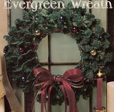 an evergreen wreath is hung on the front door with two candles and other holiday decorations