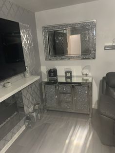 a living room with silver furniture and a large mirror on the wall above the tv