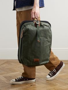 a man carrying a green bag on top of a wooden floor