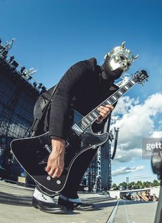 a man with a metal mask playing an electric guitar at a music festival stock photo