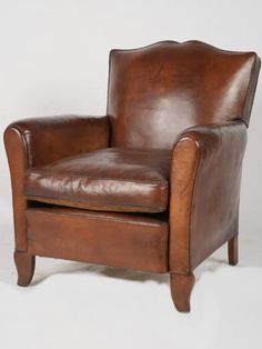 a brown leather chair sitting on top of a white floor