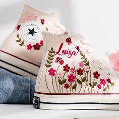 a pair of white shoes with flowers painted on the side and one shoe has blue jeans