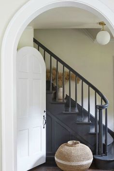 an entry way with a basket on the floor and a staircase leading up to it