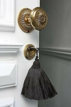 a door handle with a tassel hanging from it's side next to a white door