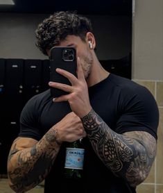 a man taking a selfie with his phone in front of him and tattoos on his arms