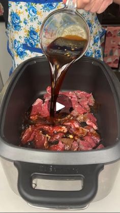 someone is pouring sauce on some meat in an air fryer