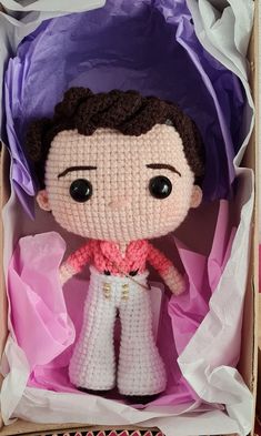 a crocheted doll in a box with tissue paper