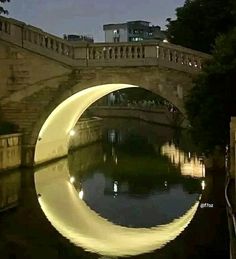 an arched bridge over a body of water at night