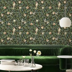 a living room with green velvet couches and floral wallpaper