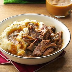 a bowl filled with meat and mashed potatoes next to a glass of orange juice