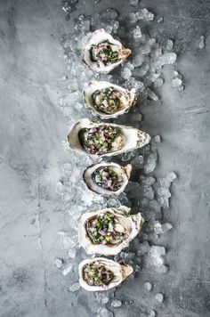 several oysters are lined up on ice with garnishes in the middle