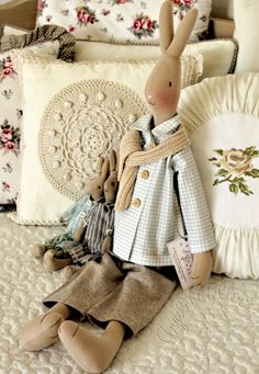 a stuffed rabbit sitting on top of a bed next to pillows and blankets with flowers