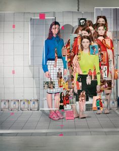 two women standing in front of a wall with pictures on it