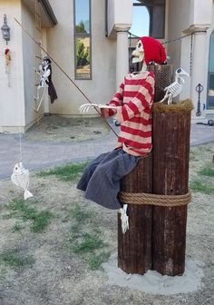 a man sitting on top of a wooden post in front of a building with skeletons