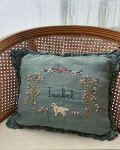 an embroidered pillow on a wicker chair with a dog in the center that says laurel