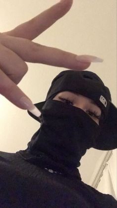 a person wearing a black hood and holding their fingers up