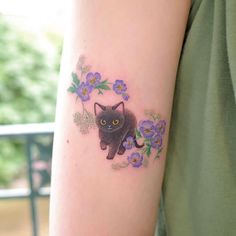 a black cat with yellow eyes and purple flowers on the left side of the arm