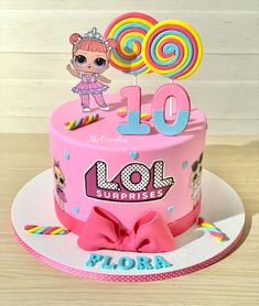 a pink birthday cake with lol surprises on top and lollipop decorations