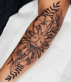 a person with a tattoo on their arm that has flowers and an animal in it