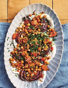 a white plate topped with carrots and chickpeas on top of a blue cloth