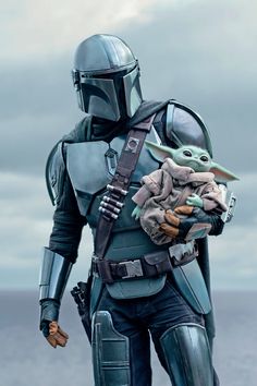 the child yoda is holding an adult star wars character in his arms and wearing a helmet