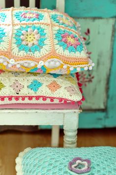 a crocheted pillow sitting on top of a white chair next to a cushion