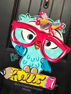 a door hanger with an owl wearing glasses and holding a pencil