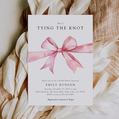 a pink bow on top of a white card with the words tying the knot above it